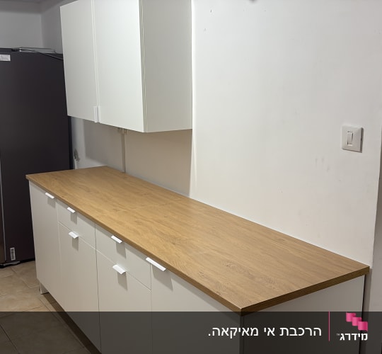ארונות מטבח עם משטח עץ ומקרר בצד